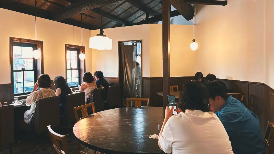 二樓保留裸露木樑的斜屋頂，有靠窗的沙發席與大圓桌