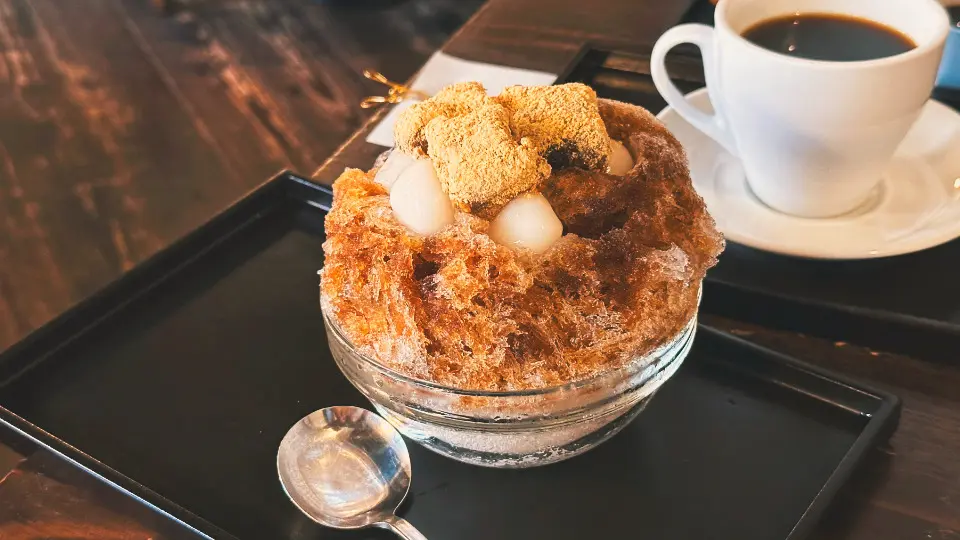 梅園黑糖白玉蕨餅刨冰，刨冰上淋滿黑糖蜜，搭配Q彈白玉與入口即化的蕨餅，是京都夏季必吃的消暑甜點